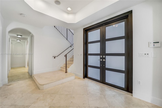 entryway featuring stairs, baseboards, arched walkways, and french doors