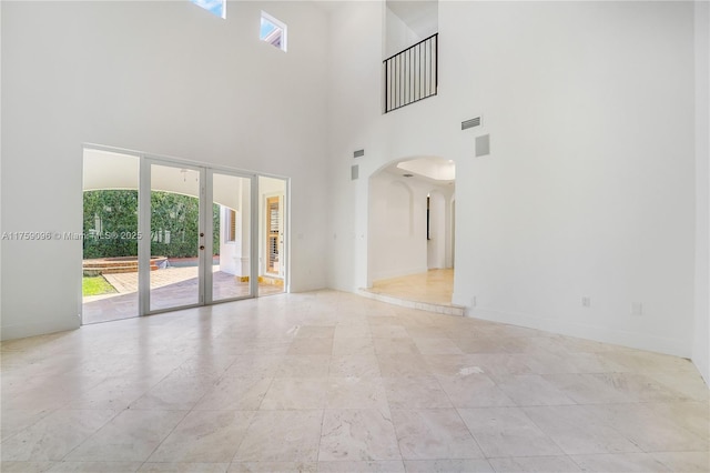 unfurnished room featuring arched walkways, french doors, visible vents, and baseboards