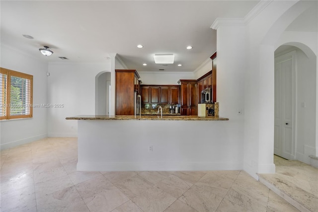 kitchen featuring arched walkways, stainless steel appliances, ornamental molding, and stone countertops