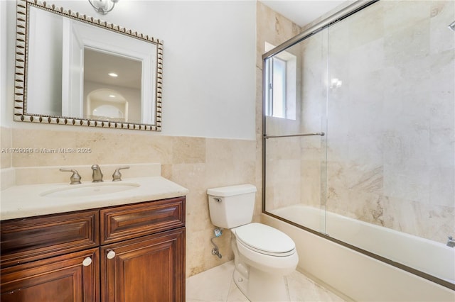 full bath with bath / shower combo with glass door, toilet, tile patterned floors, vanity, and tile walls