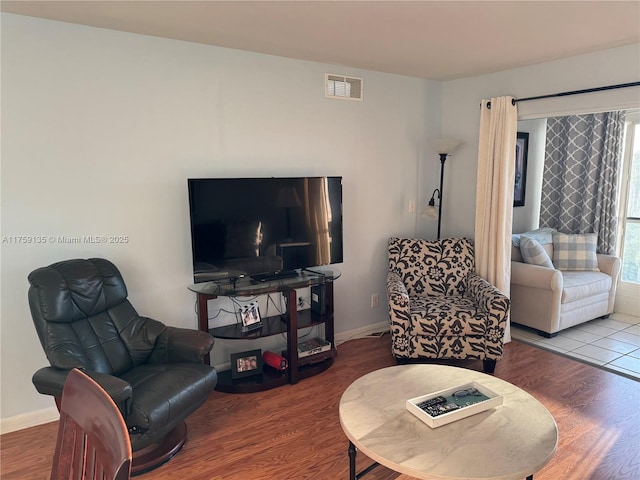 living area featuring wood finished floors, visible vents, and baseboards