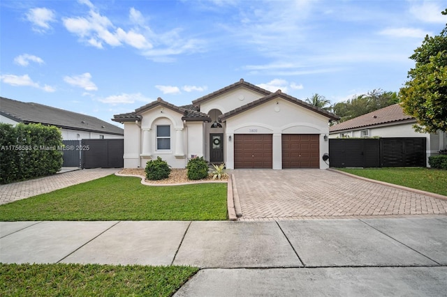 mediterranean / spanish house featuring a garage, fence, decorative driveway, stucco siding, and a front yard