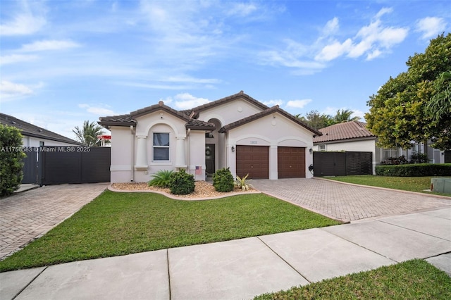 mediterranean / spanish home featuring a garage, stucco siding, fence, decorative driveway, and a front yard