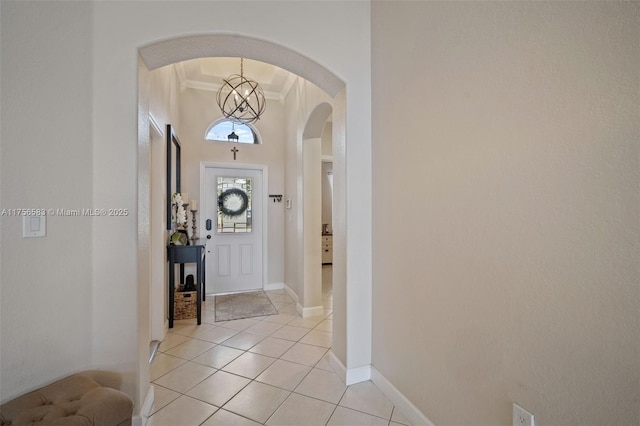 foyer entrance featuring light tile patterned floors, baseboards, ornamental molding, and arched walkways