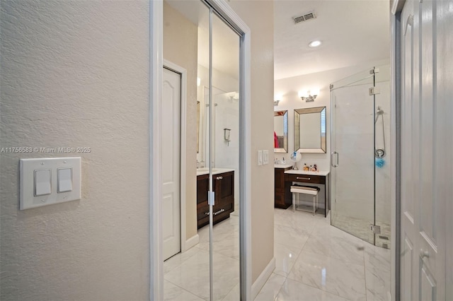 bathroom with visible vents, a textured wall, marble finish floor, vanity, and a shower stall