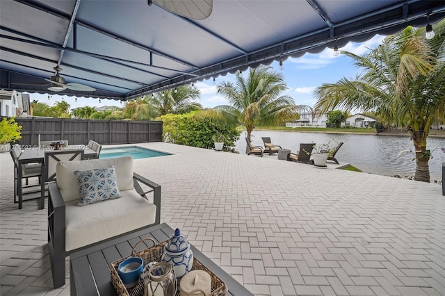 view of patio featuring a water view, a fenced in pool, and outdoor dining space