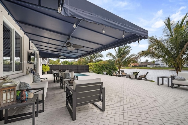 view of patio / terrace featuring a water view, fence, an outdoor hangout area, and a ceiling fan