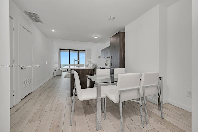 dining room with baseboards, visible vents, and light wood finished floors