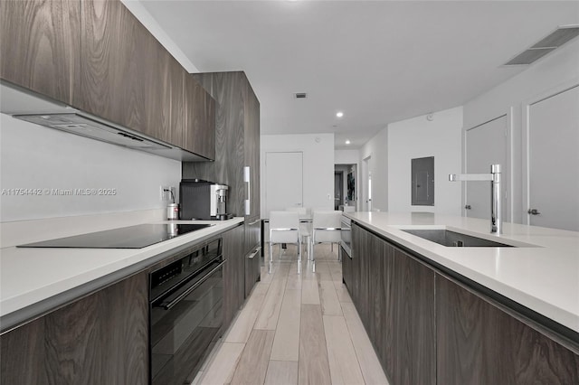 kitchen featuring light countertops, visible vents, a sink, modern cabinets, and black appliances