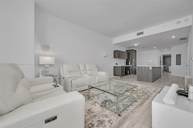 living room featuring electric panel, visible vents, and light wood finished floors