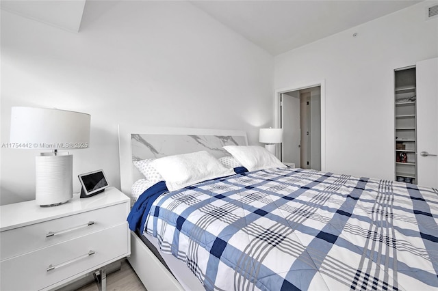 bedroom with visible vents, vaulted ceiling, a closet, light wood finished floors, and a walk in closet