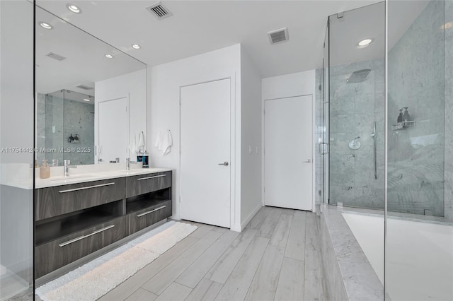 bathroom featuring a sink, a stall shower, wood finished floors, and visible vents