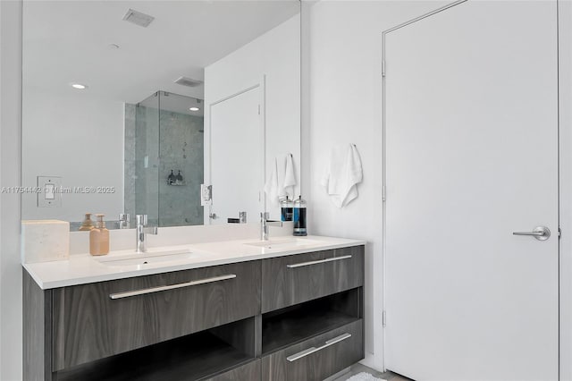 bathroom featuring visible vents, a sink, a shower stall, and double vanity