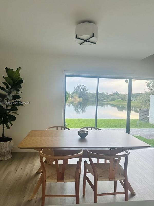 dining space featuring a water view, wood finished floors, and a wealth of natural light