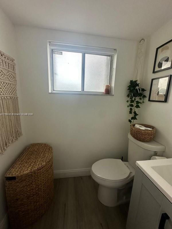 bathroom with toilet, baseboards, wood finished floors, and vanity