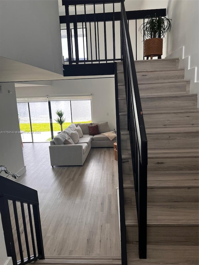 staircase with a towering ceiling and wood finished floors