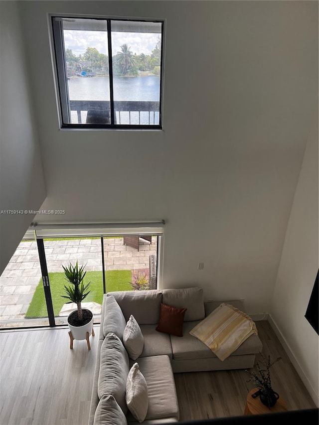 living area featuring a water view, baseboards, and wood finished floors