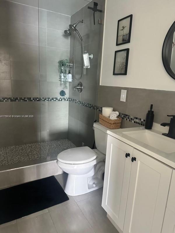 bathroom with decorative backsplash, toilet, tile patterned flooring, vanity, and a shower stall