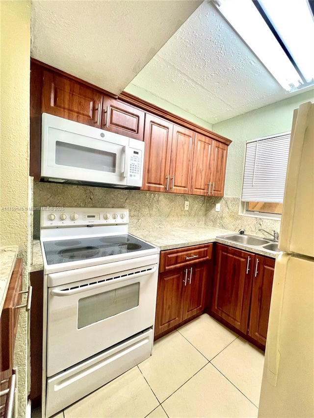 kitchen with white appliances, light tile patterned floors, a sink, light countertops, and backsplash