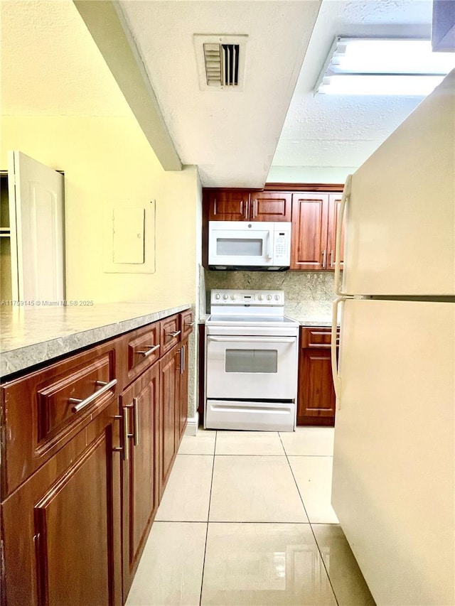 kitchen with white appliances, light tile patterned floors, visible vents, decorative backsplash, and light countertops