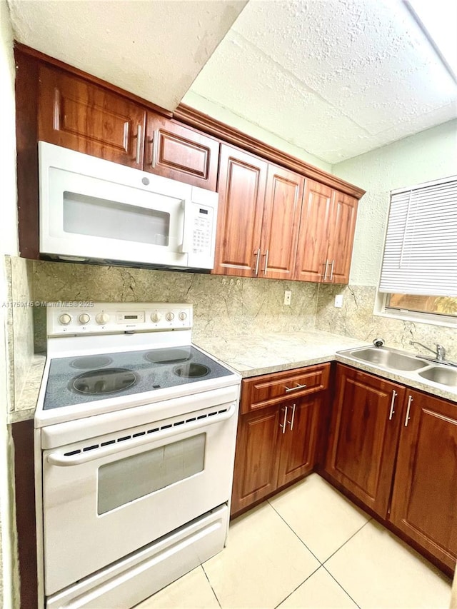 kitchen featuring light countertops, light tile patterned floors, decorative backsplash, white appliances, and a sink