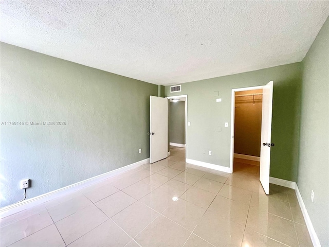 unfurnished bedroom featuring light tile patterned floors, baseboards, visible vents, and a textured ceiling