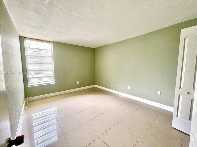 unfurnished room with tile patterned flooring, baseboards, and a textured ceiling