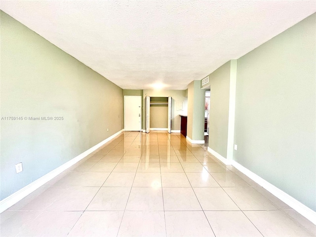 unfurnished room featuring light tile patterned floors, baseboards, and a textured ceiling