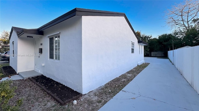 view of side of property with fence and stucco siding