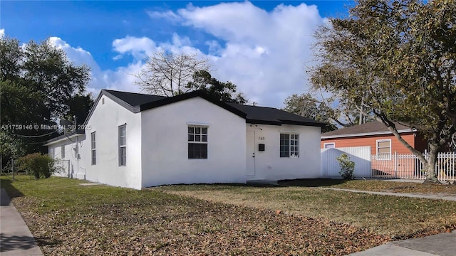 view of front of home featuring stucco siding, a front lawn, and fence