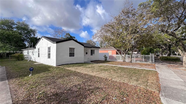 view of property exterior featuring a lawn, fence, and stucco siding