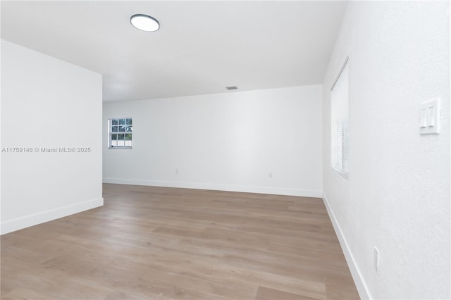 empty room featuring visible vents, light wood-style flooring, and baseboards