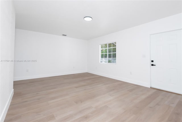 unfurnished room featuring visible vents, light wood-style flooring, and baseboards