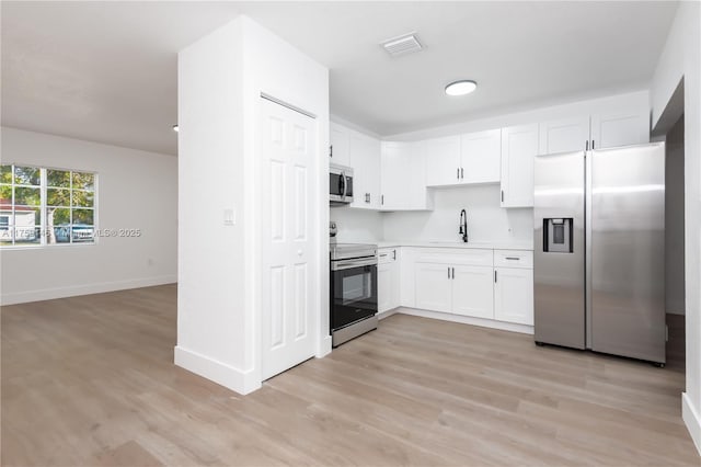 kitchen with stainless steel appliances, light wood-style floors, visible vents, and white cabinets