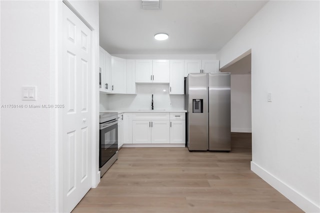 kitchen with visible vents, appliances with stainless steel finishes, white cabinets, and a sink