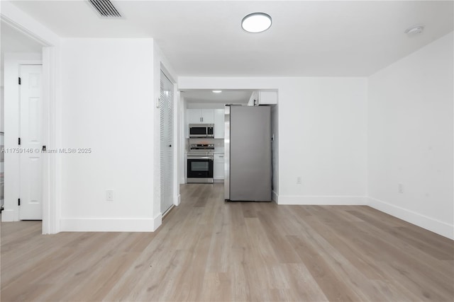 unfurnished living room featuring visible vents, light wood-style flooring, and baseboards