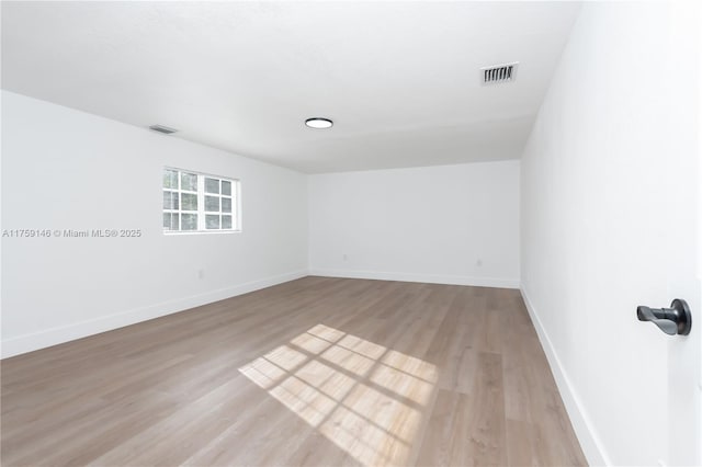 empty room featuring visible vents, light wood-type flooring, and baseboards