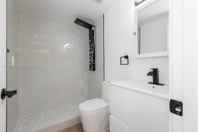bathroom featuring vanity, toilet, and tiled shower