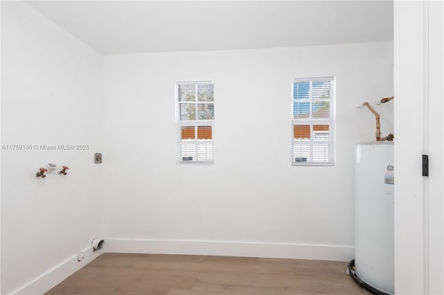 washroom with baseboards, laundry area, water heater, washer hookup, and light wood-type flooring