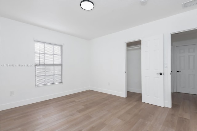unfurnished bedroom featuring light wood-type flooring, visible vents, baseboards, and a closet