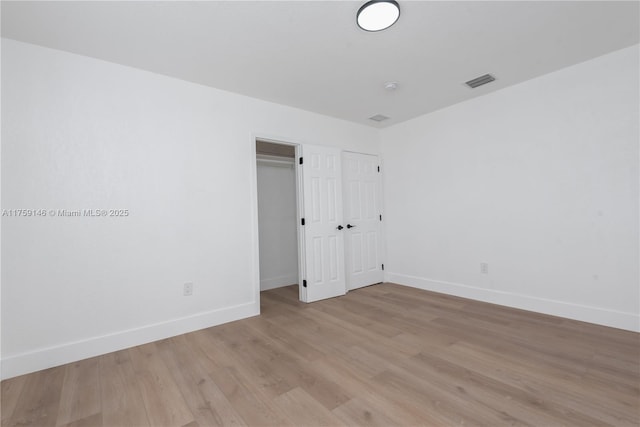 empty room with light wood-style flooring, visible vents, and baseboards