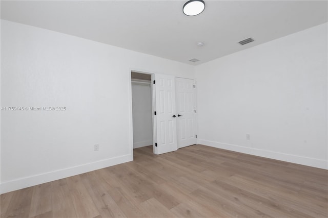 unfurnished room with visible vents, light wood-style flooring, and baseboards