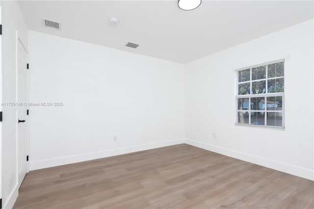 spare room with light wood-style flooring, visible vents, and baseboards