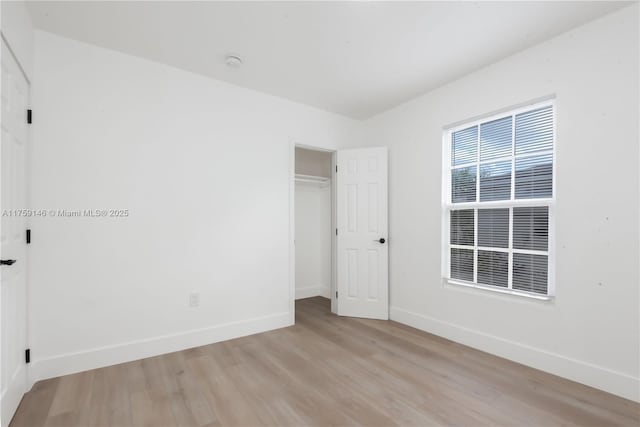 unfurnished bedroom featuring a closet, light wood-style flooring, and baseboards