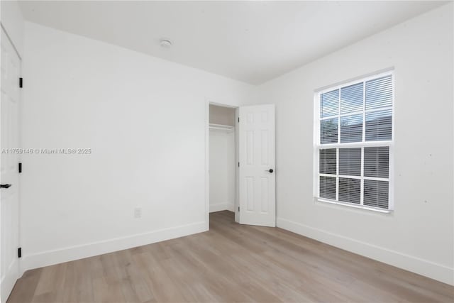 unfurnished bedroom featuring a closet, baseboards, and light wood finished floors
