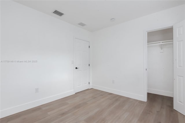 unfurnished bedroom with light wood-type flooring, baseboards, and a closet