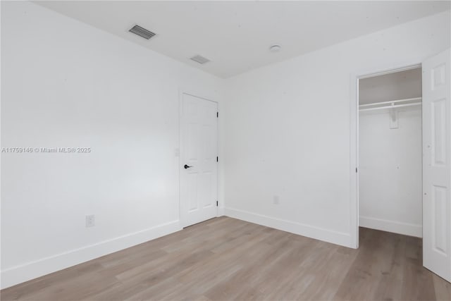 unfurnished bedroom featuring light wood-style floors, baseboards, and a closet