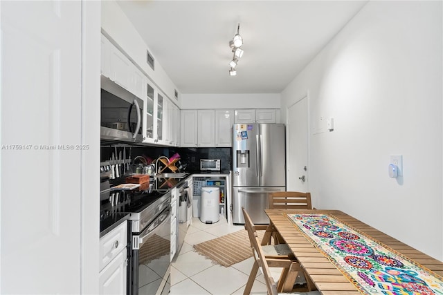 6770 Indian Creek Dr Unit 5K, Miami Beach, FL 33141 - kitchen with white cabinetry, light tile patterned flooring, decorative backsplash, stainless steel appliances, and a sink