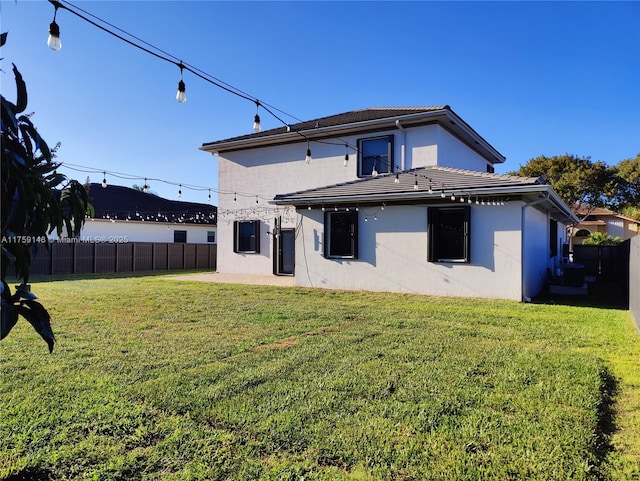 rear view of house featuring a yard, a patio, a fenced backyard, and stucco siding