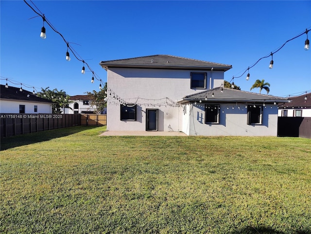 back of house featuring stucco siding, a lawn, and a fenced backyard